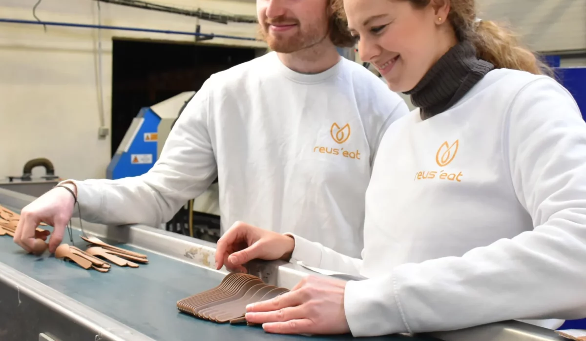Fondateurs de Reus'eat (Marie Nagy et Armand Ferro) devant un tapis roulant industriel de leur production de kits de couverts de voyage français et naturels